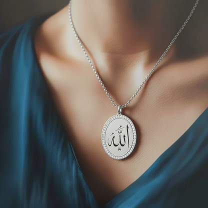 Silver necklace with a pendant featuring Arabic text, worn by a person in a blue garment.